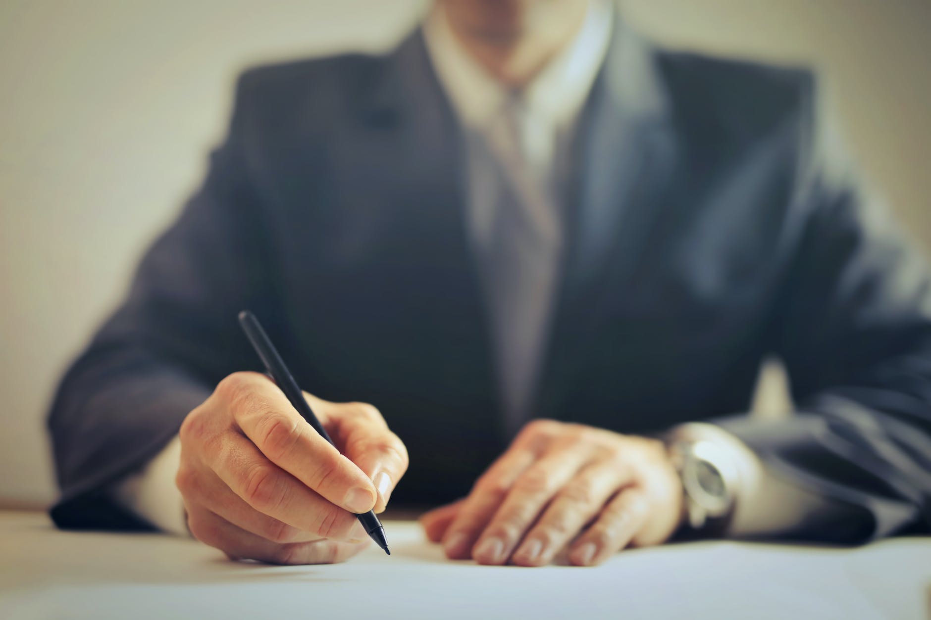 A blurred image of a smart manager in a jacket holding a pen.