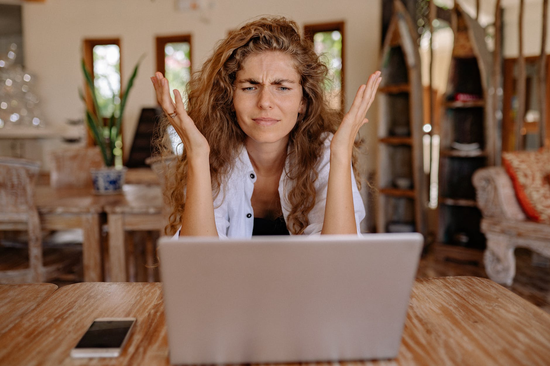 Woman appearing baffled working in front of a laptop.